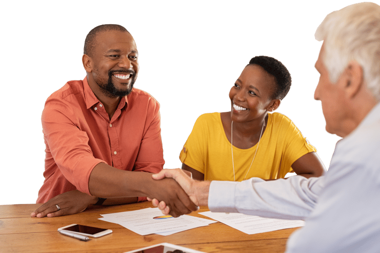 A couple shaking hands with a salesman over a table with paperwork A couple shaking hands with a salesman over a table with paperwork